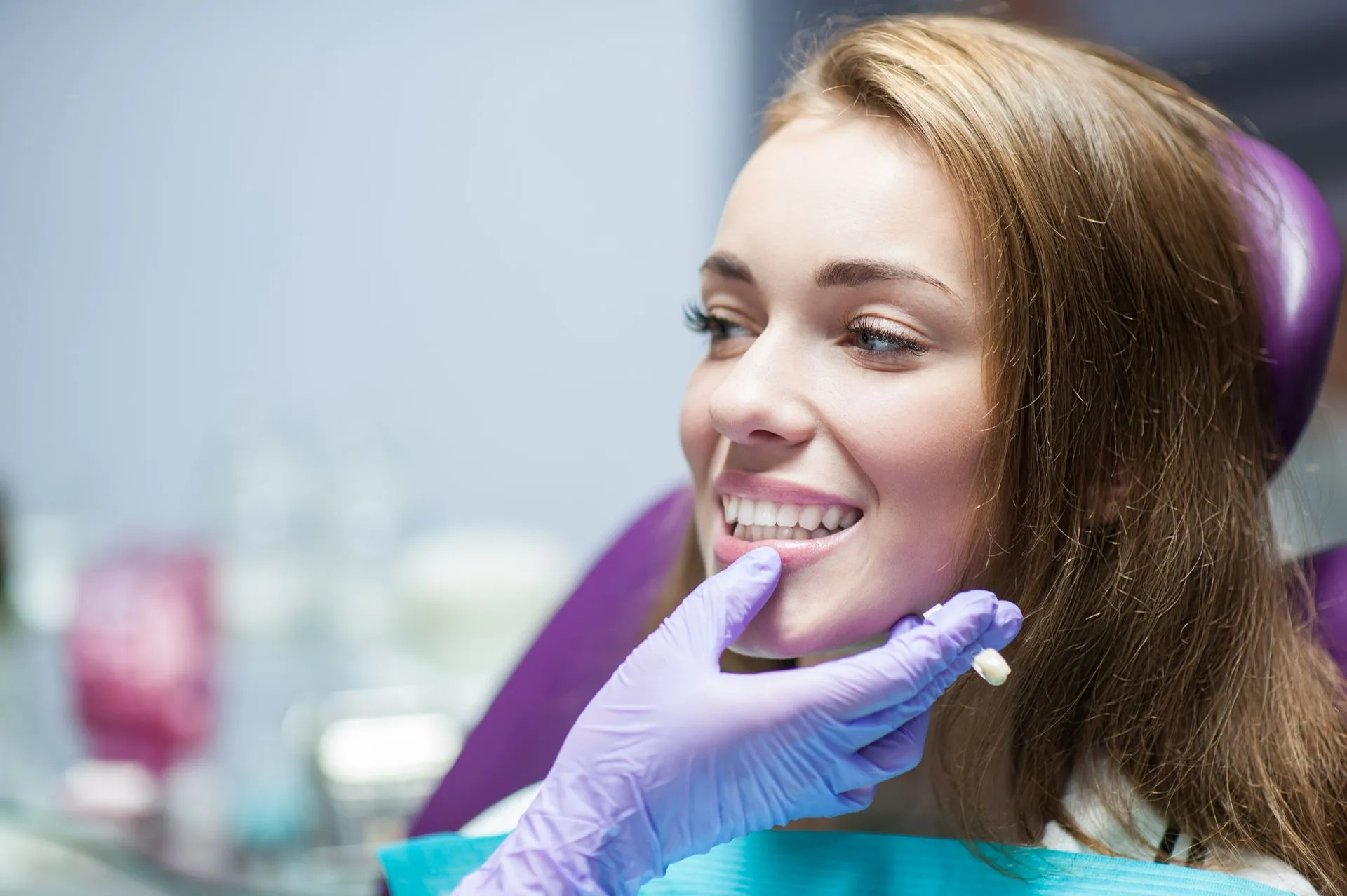 Dentist wearing gloves examining a patient’s mouth before preparing a dental crown.